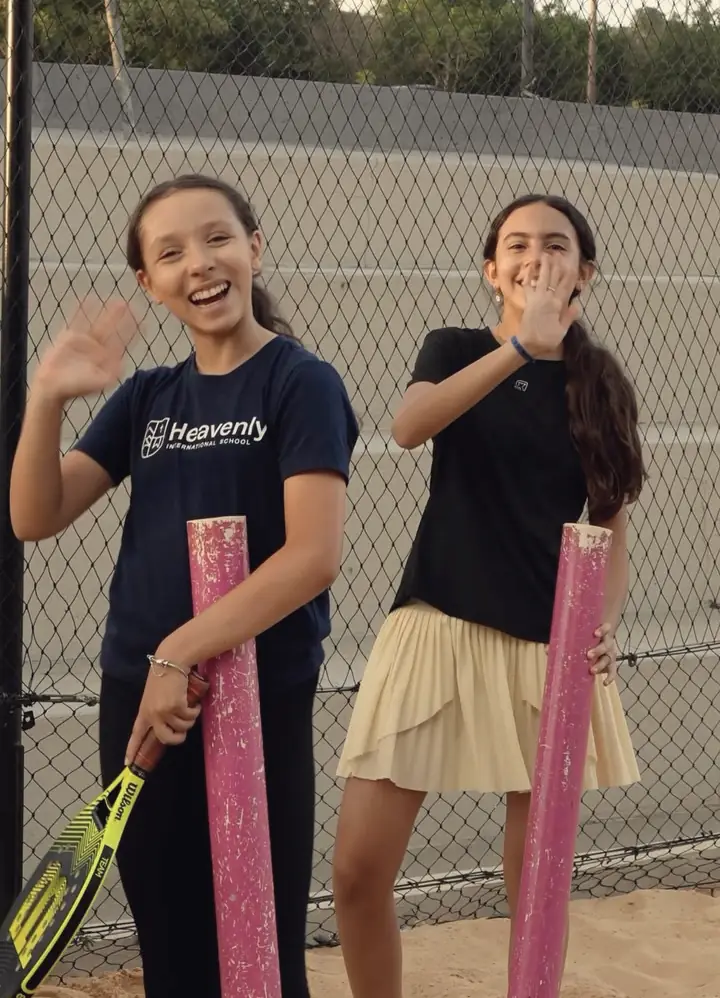 Duas alunas da turma kids acenando com as raquetes