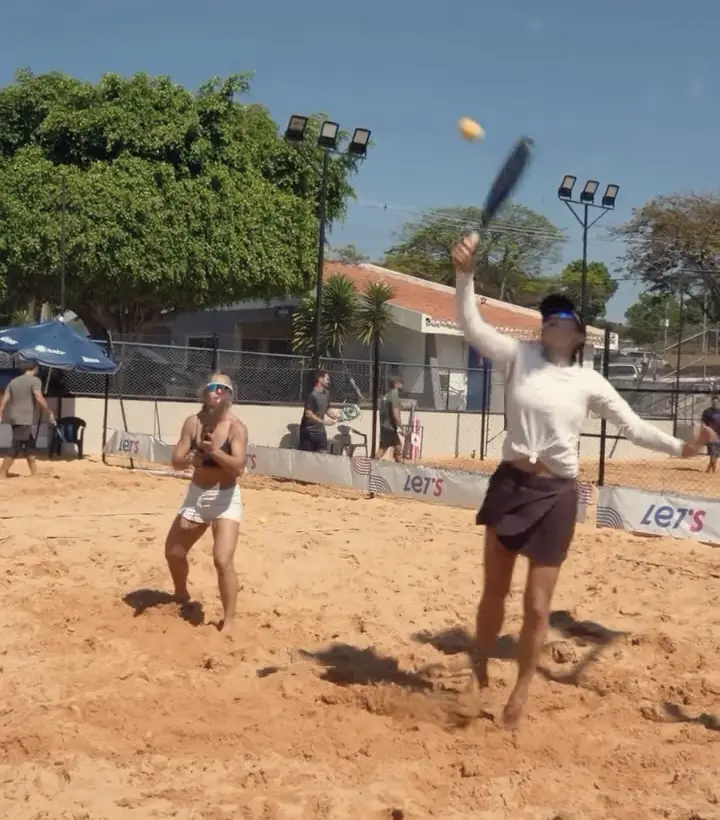 Dupla em jogo na quadra, bola no alto