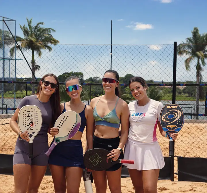 Quatro alunas com raquetes na quadra, céu azul